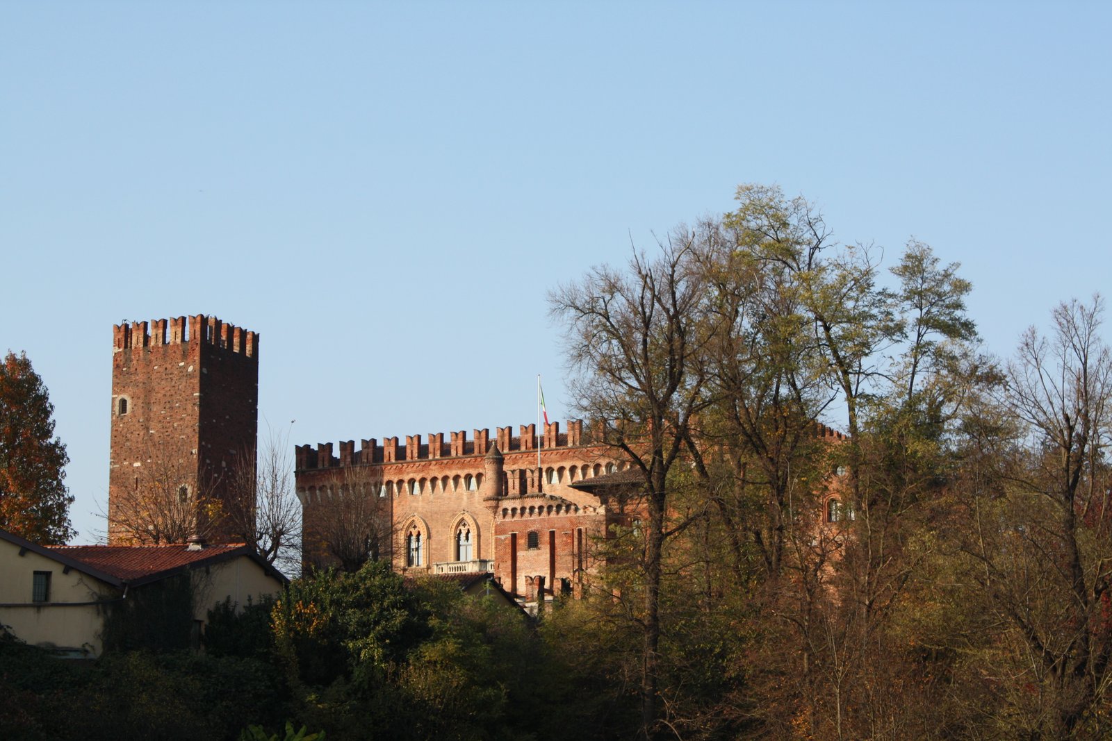 Il Castello di Carimate visto da lontano, con il corpo merlato e la torre angolare che emergono sopra le chiome degli alberi